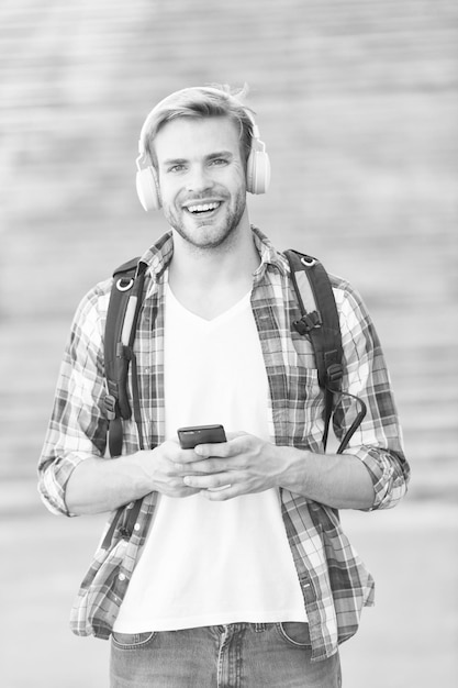 Tenha algumas dicas Jovens modernos e digitais homem feliz Estudante universitário fones de ouvido Smartphone Educação online Conceito de livro de áudio Estudante de tecnologia educacional e aprendendo a vida escolar Ouvir música