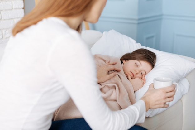 Tenha um bom sono. menina pacífica e agradável dormindo enquanto sua mãe está sentada perto e cuidando dela