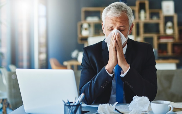 Tenho que estocar lenços foto de um empresário frustrado usando um lenço para espirrar enquanto está sentado no escritório