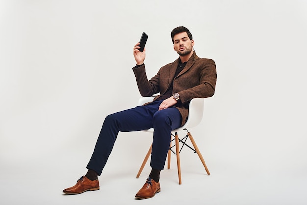 Tenho uma ideia de um homem elegante de cabelos escuros sentado em uma cadeira segurando um telefone