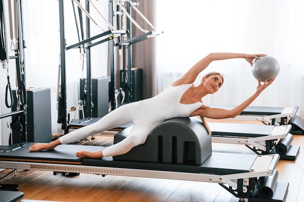 Foto teniendo la pelota en las manos una mujer joven en el gimnasio está haciendo ejercicios