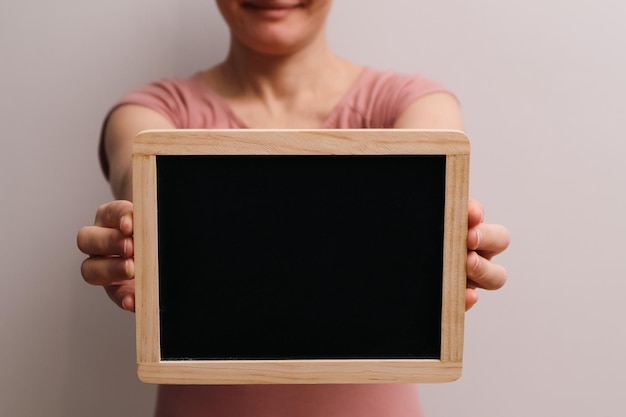 Teniendo una pizarra en blanco Mujer mostrando una pizarra cortada imagen de mujer sosteniendo una tablilla negra vacía