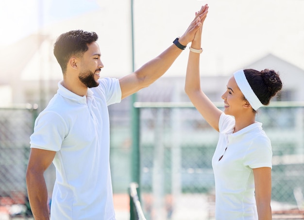 Tenis alto cinco y motivación con una pareja deportiva en celebración de un logro como equipo ganador Entrenamiento físico y éxito con un hombre y una mujer tenista en una cancha de tenis juntos