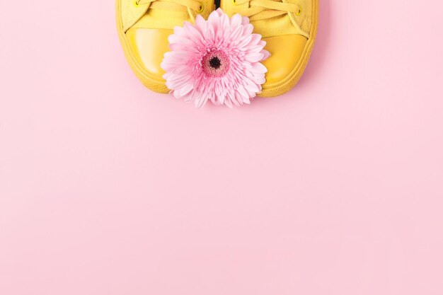 Tênis amarelo e flor rosa gerbera. Layout mínimo para redes sociais com lugar para texto ou produto em tons pastel.
