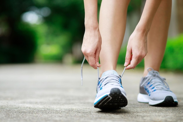 Tênis de corrida fecham atleta feminina amarrando cadarços para correr na estrada gravatas de corredor se preparando para treinar banner de espaço de cópia de estilo de vida esportivo