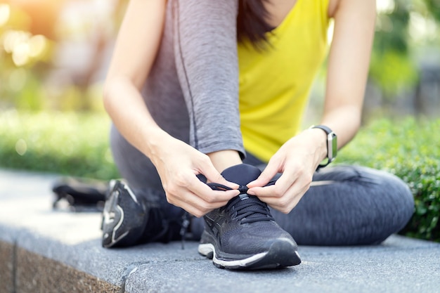 Tênis de corrida - mulher amarrar cadarços de sapato, corredor de aptidão desportiva se preparando para correr no jardim.