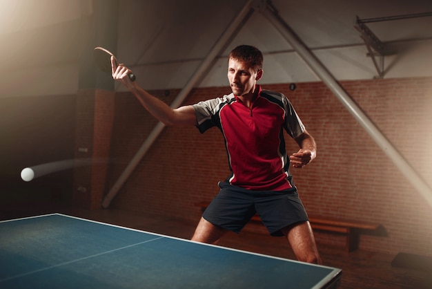 Tênis de mesa, jogador masculino com raquete em ação, bola com rastro. treinamento de pingue-pongue interno