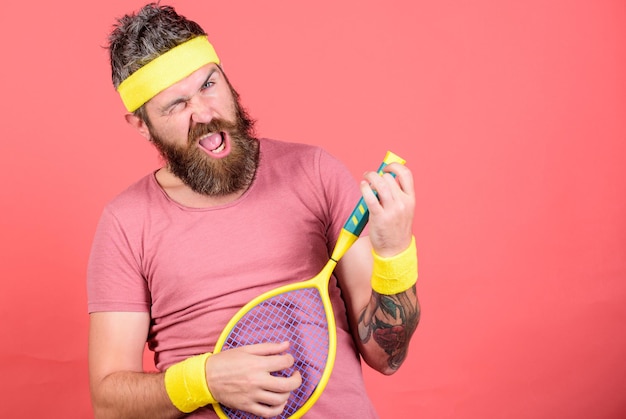 Tênis esporte e entretenimento Homem barbudo hipster usar roupa esportiva se divertindo Tênis lazer ativo Atleta hipster segurar a raquete de tênis na mão fundo vermelho Jogador de tênis moda vintage