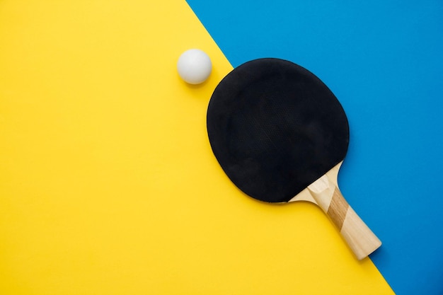 Tenis de mesa o raqueta de ping pong y pelota sobre fondo azul y amarillo