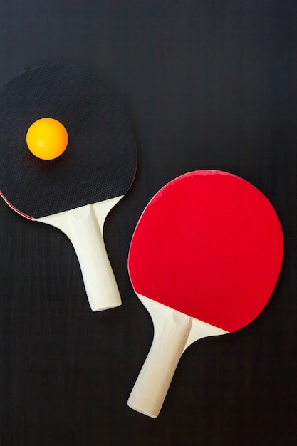 Tenis de mesa o raquetas de ping pong y pelota sobre un fondo negro