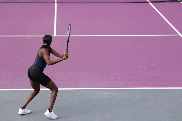 Foto tenista afroamericana en acción en la cancha en un día soleado