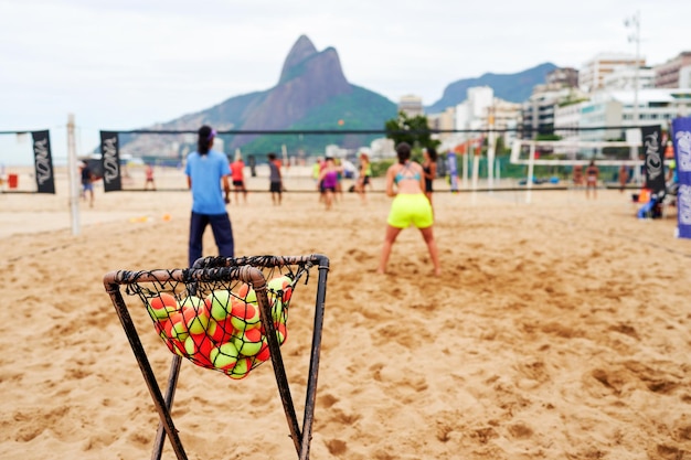 Tennisbälle in einem Korb am Strand mit Menschen, die Beach-Tennis im Hintergrund in Ipanema spielen