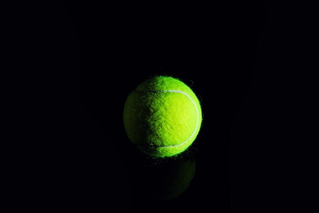 Tennisball isoliert auf Schwarz mit dramatischer Beleuchtung