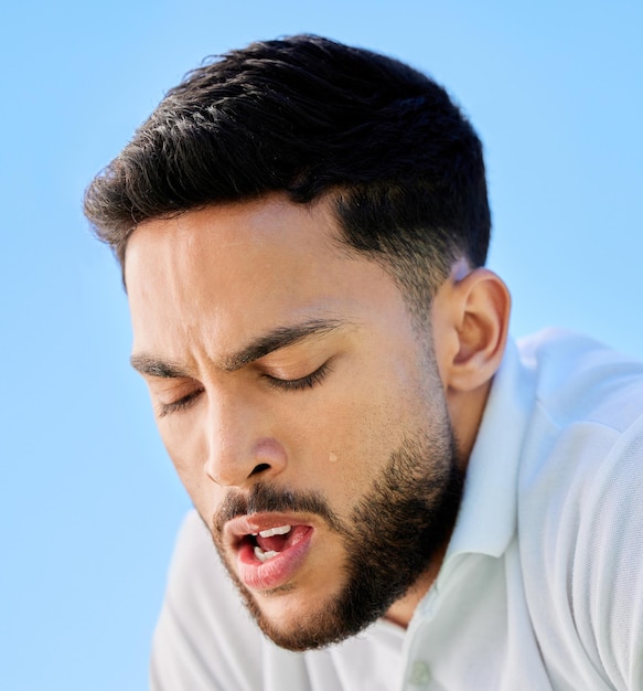 Tennisfitness und müdes Manngesicht oder Ermüdung durch Cardio-Workout oder Training Atmungsermüdung und gesunder Sportmann entspannen oder ruhen sich in einer Pause vom Sporttraining mit blauem Himmel aus