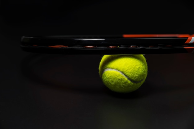 Foto tennisschläger mit ball auf schwarzem hintergrund