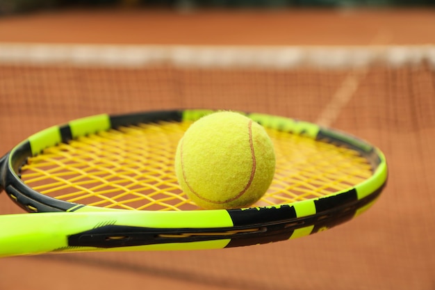 Tennisschläger mit Tennisball gegen Sandplatz