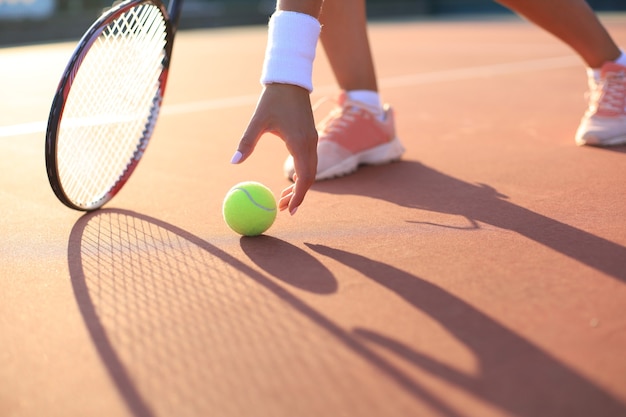 Tennisspieler hebt während des Spiels einen Tennisball vom Sandplatz.