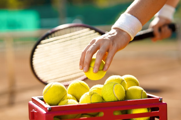 Tennisspieler nimmt einen Ball aus einem Korb