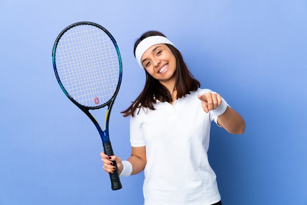 Tennisspielerin der jungen Frau über der Wand, die vorne mit glücklichem Ausdruck zeigt