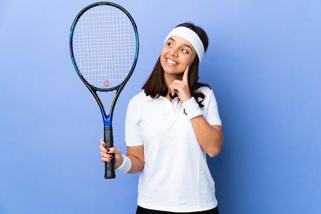 Tennisspielerin der jungen Frau über Wand, die eine Idee beim Aufschauen denkt