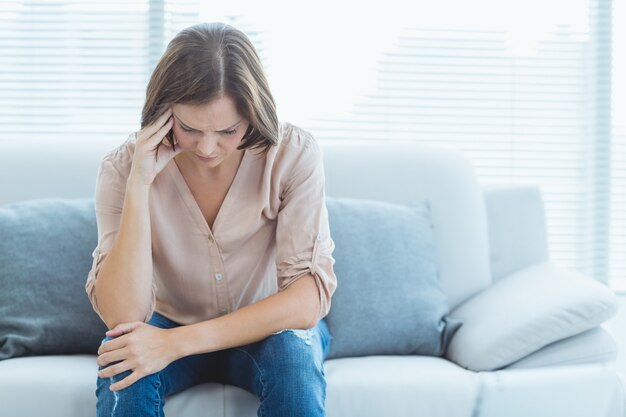 Tensa mujer sentada en el sofá