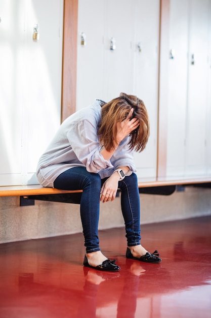 Tensa mujer sentada en el vestuario