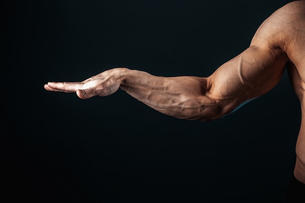 Foto tenso brazo, venas, músculos culturista sobre un fondo oscuro, aislar