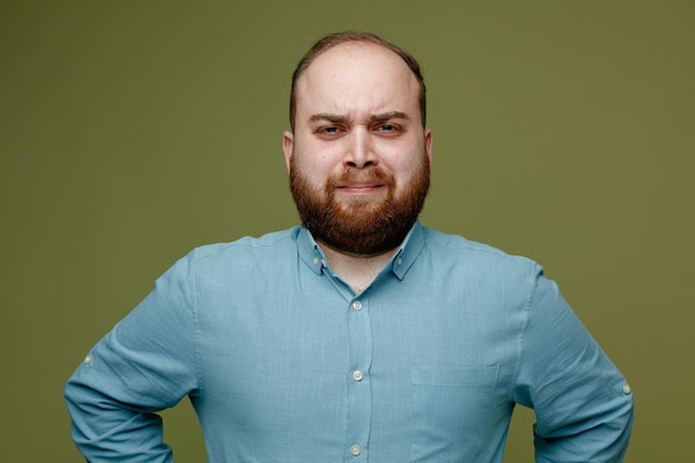 Tenso jovem bonitão vestindo camisa azul isolada em fundo verde