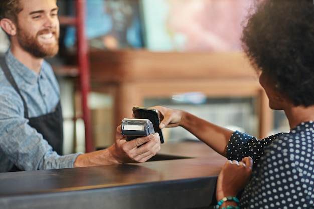 Foto tentamos tornar sua experiência o mais conveniente possível foto de um barista recebendo um pagamento por smartphone de um cliente em um café