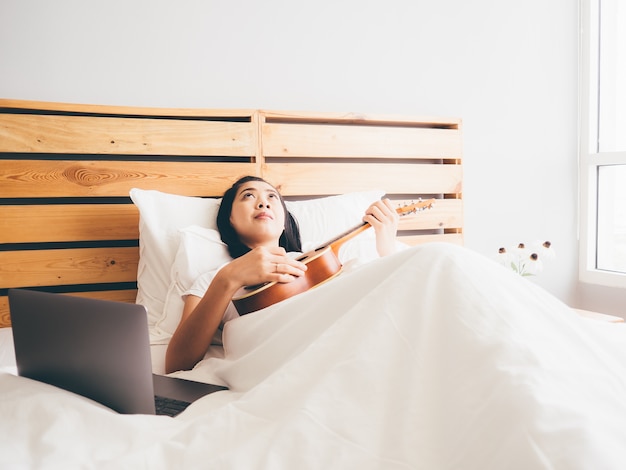 Tentativa da mulher para aprender o ukulele em seu quarto.