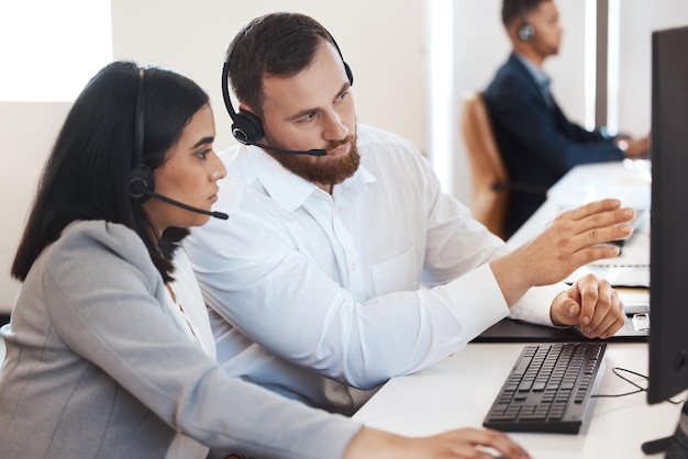 Foto tente fazer assim da próxima vez foto de dois agentes de call center trabalhando juntos em um computador em um escritório