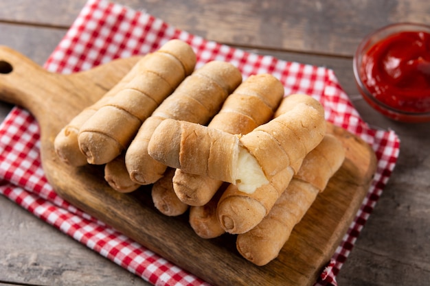 Tequeos latinoamericanos rellenos de queso sobre mesa de madera