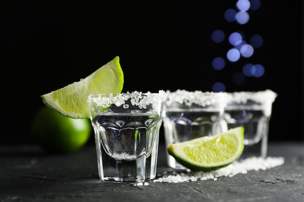 Tequila-Aufnahmen mit Salz- und Limettenscheiben auf Schwarz