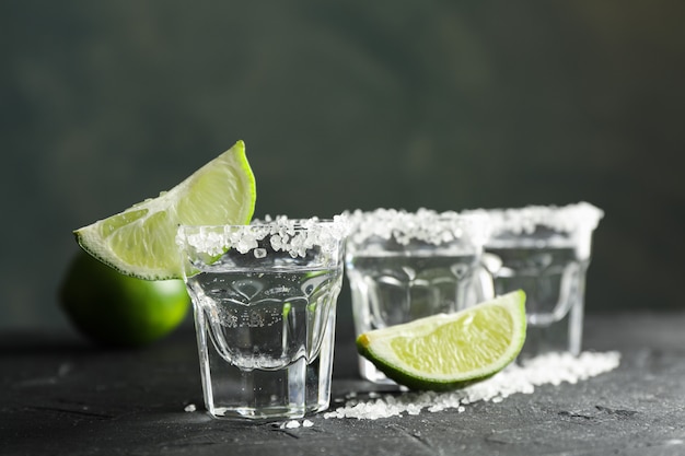 Tequila-Aufnahmen mit Salz- und Limettenscheiben auf Schwarz
