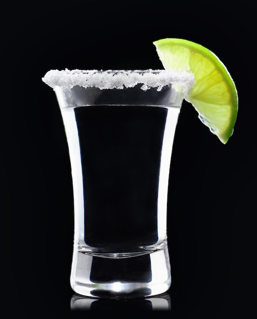 tequila disparada con rodaja de lima y sal sobre un fondo negro