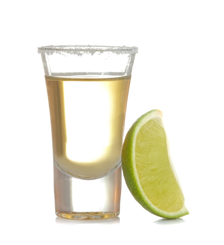 Foto tequila dourada em um copo com close-up de limão em um fundo branco isolado