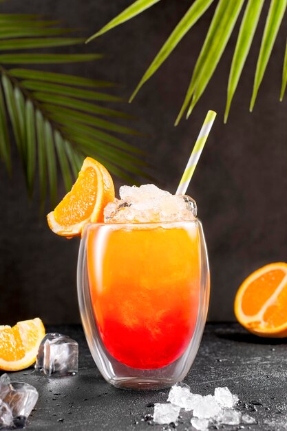 Tequila fresca al amanecer con paja y rebanadas de naranja en el borde del vidrio en la mesa negra bebida alcohólica