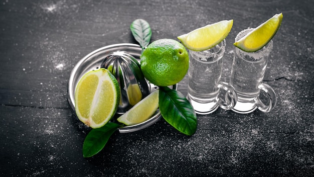 Tequila con lima limón y sal sobre un fondo negro Madera Espacio libre para texto Vista superior