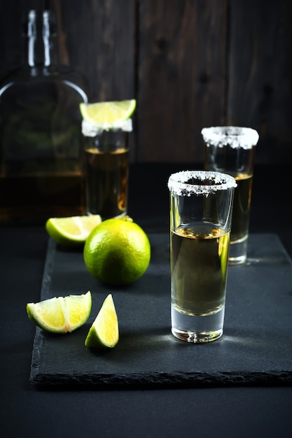 Tequila de oro con limón y sal sobre una superficie oscura. Enfoque selectivo.