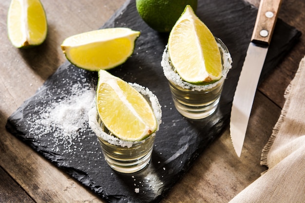 Tequila de oro mexicano con limón y sal de mesa de madera