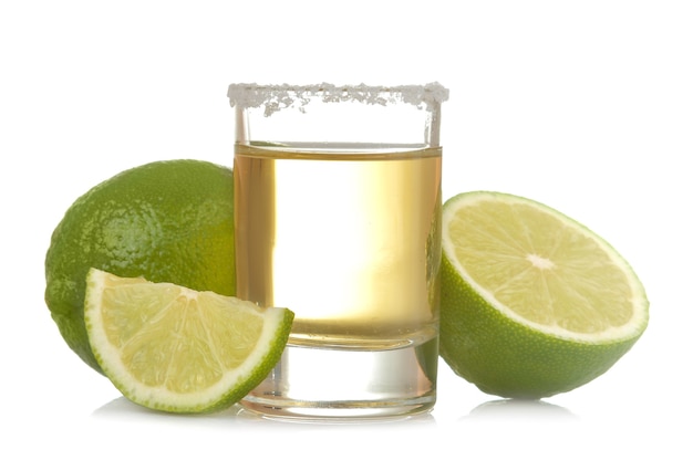 Tequila de oro en un vaso con limón de cerca sobre un fondo blanco aislado