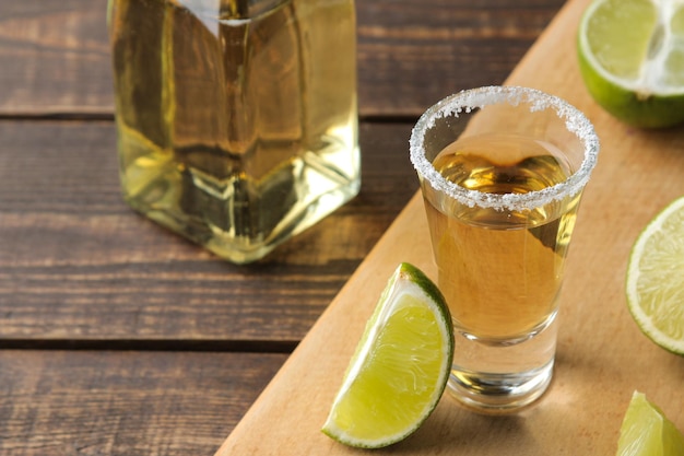 Tequila de oro en un vaso con sal y limón sobre una mesa de madera marrón. bebidas alcohólicas.