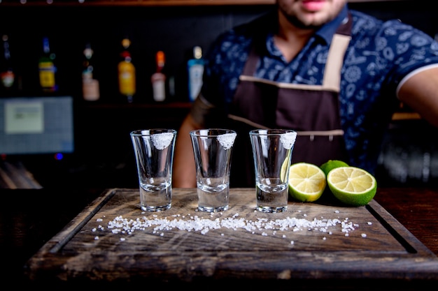 Tequila prata, álcool em copos de shot, limão e sal, imagem enfraquecida, foco seletivo