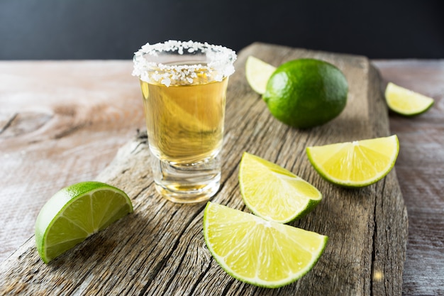 Tequila schoss mit Kalk auf rustikalem hölzernem Hintergrund