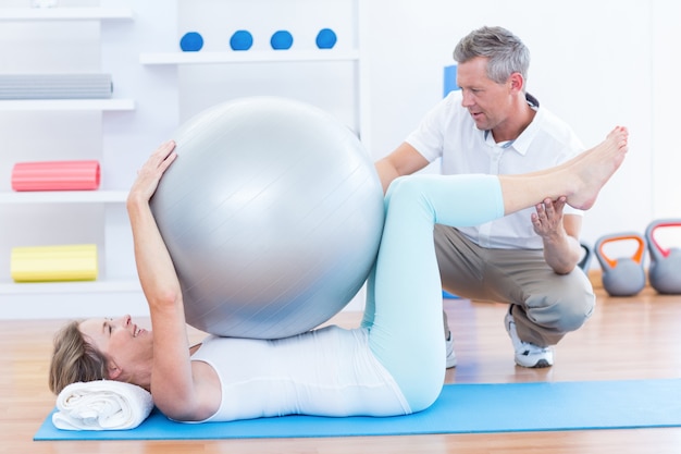 Terapeuta ajudando o paciente com bola de exercício
