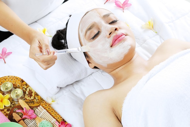 Foto terapeuta aplicando creme de máscara facial no rosto de mulher