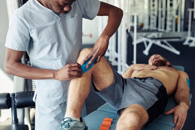 Foto terapeuta aplicando fitas médicas no paciente