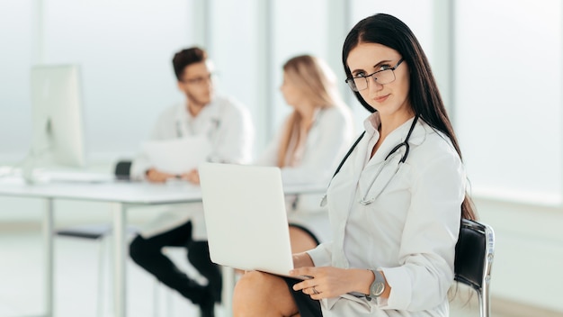 Terapeuta com um laptop sentado no escritório do hospital. Foto com espaço de cópia