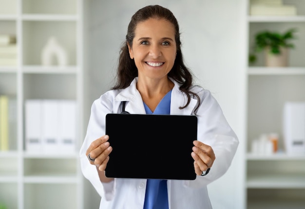 Terapeuta de mulher feliz segurando tablet digital com tela vazia