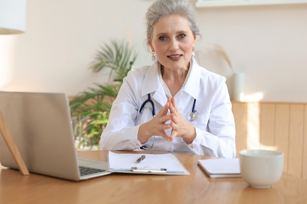 Terapeuta do médico da mulher idosa usando videochamada de fone de ouvido falando com uma câmera da web, consultando o paciente virtual on-line por bate-papo de videoconferência.